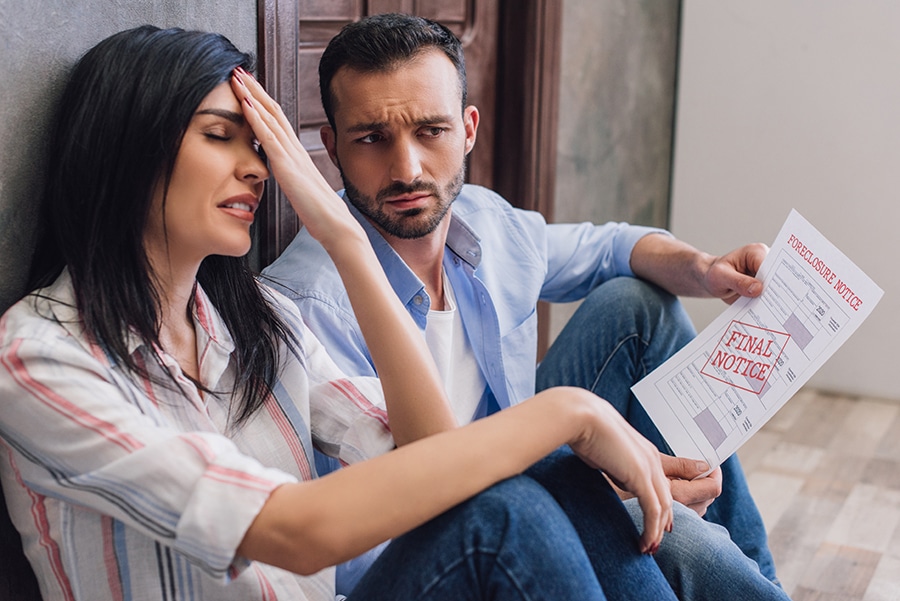 Stressed woman with husband holding foreclosure notice